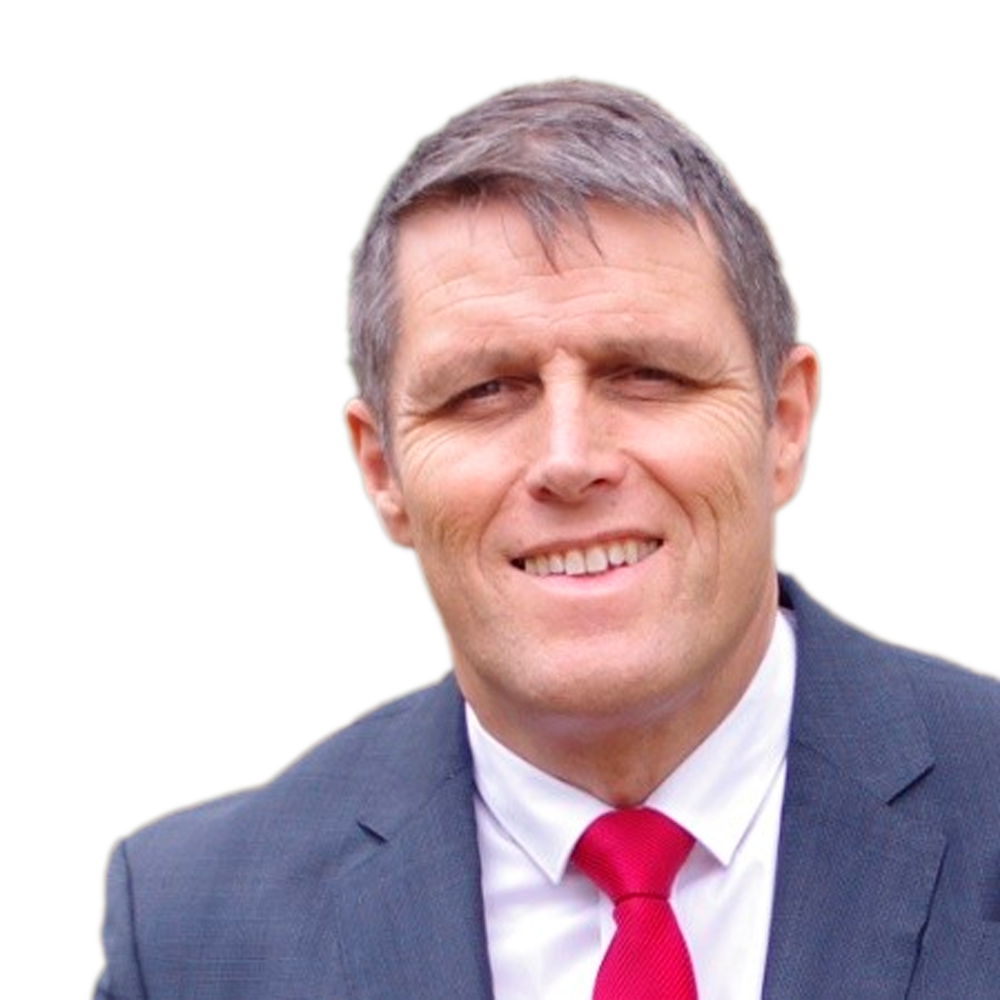 Profile picture of a person with short hair and a beard, wearing a black vest and white shirt, with a blurred outdoor background