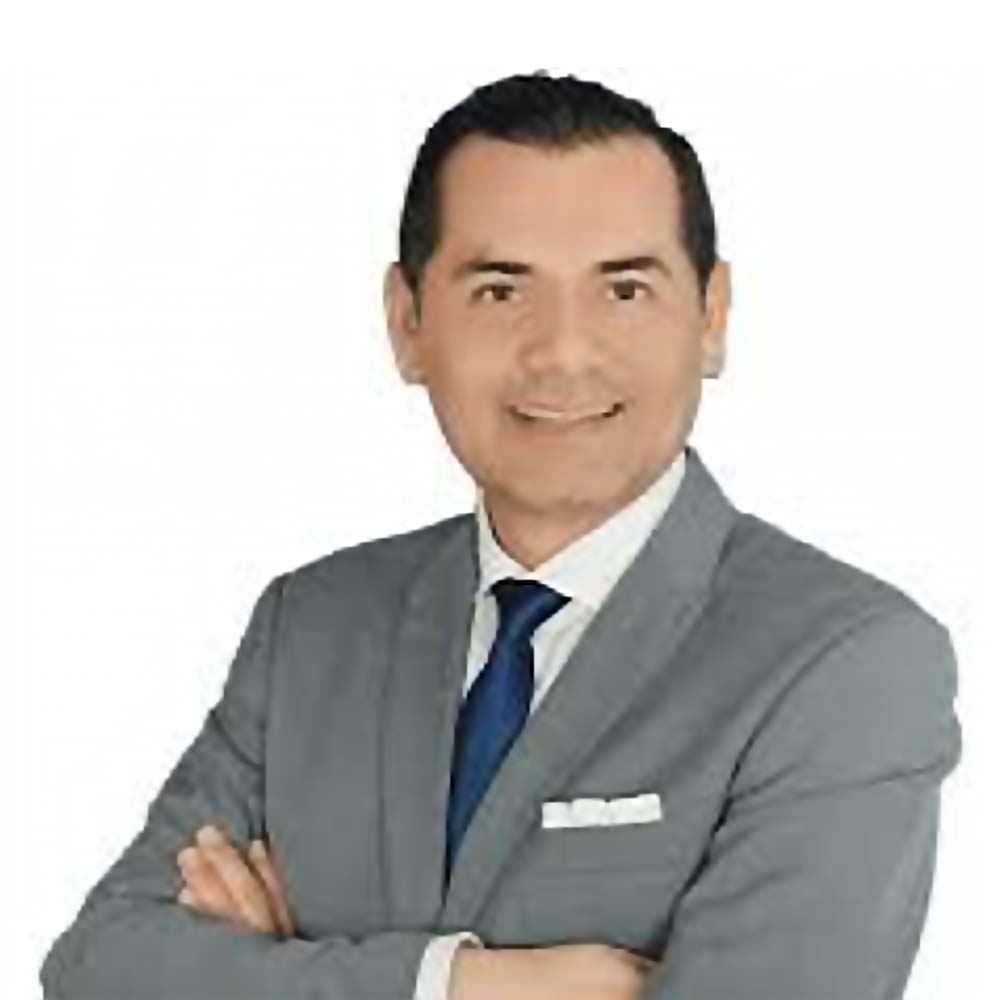 Profile picture of a person with short hair and a beard, wearing a black vest and white shirt, with a blurred outdoor background