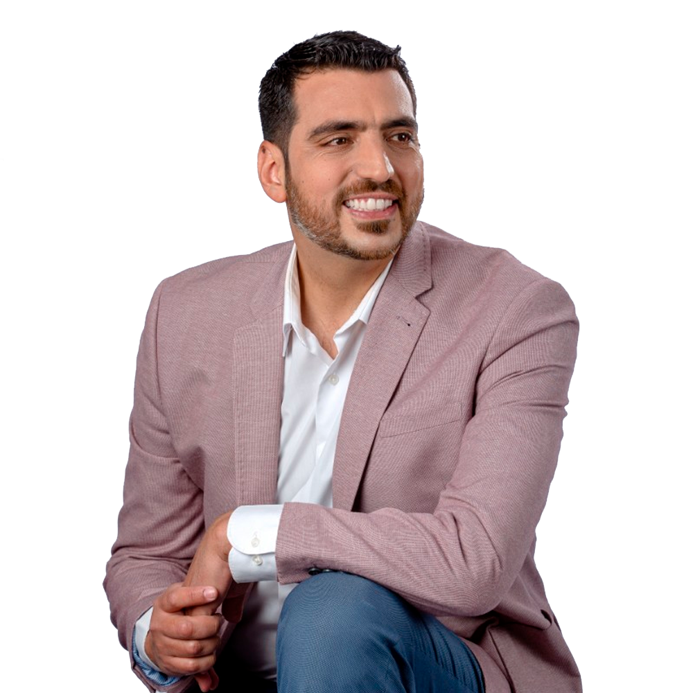 Profile picture of a person with short hair and a beard, wearing a black vest and white shirt, with a blurred outdoor background